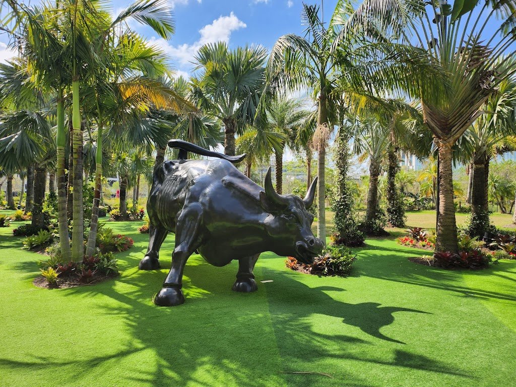 metal bull on green grass and trees surrounding it
